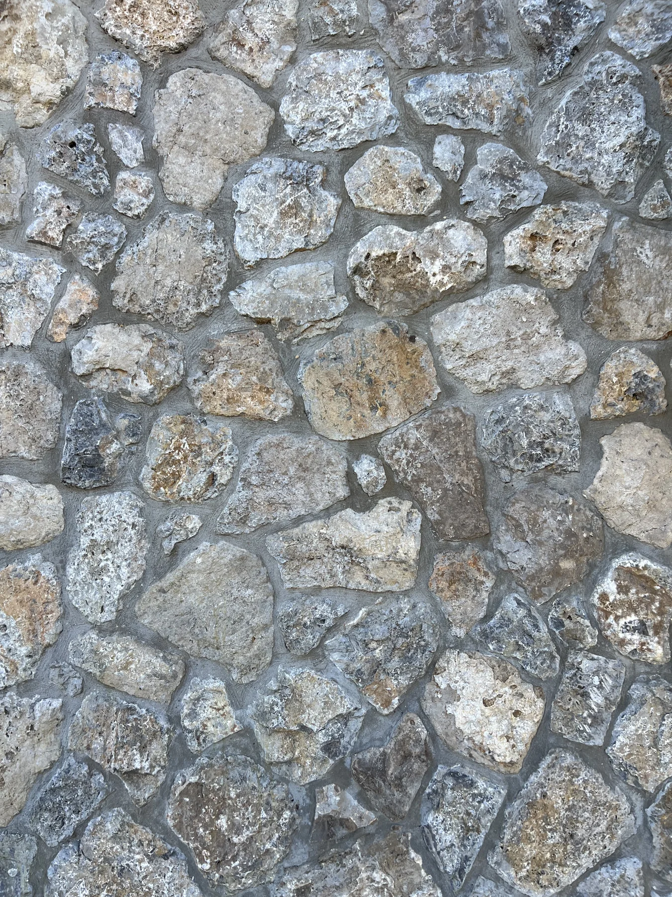 Dry stone wall texture — irregular limestone blocks, pale grey mortar
